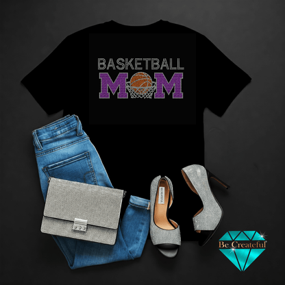 Black t-shirt with 'Basketball Mom' rhinestone design, blue jeans, rhinestone handbag, and high heels on a dark background.