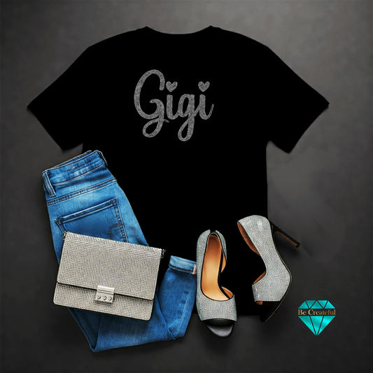 Black rhinestone t-shirt with  'Gigi' text, blue jeans, on a dark background.