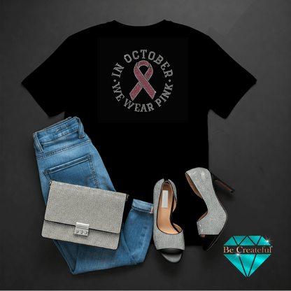 Black t-shirt with pink ribbon design, blue jeans, silver handbag, and high heels on a dark background.