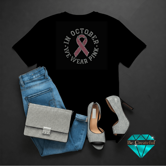 Black t-shirt with pink ribbon design, blue jeans, silver handbag, and high heels on a dark background.