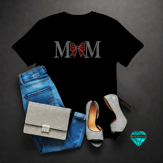 Black t-shirt with 'MOM' design, blue jeans, silver handbag, and high heels on a dark background.