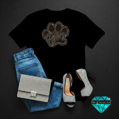 Black t-shirt with paw print design, blue jeans, silver handbag, and high heels on a dark background.