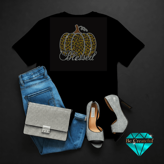 Black t-shirt with pumpkin design and 'Blessed' text, paired with blue jeans, silver handbag, and high-heeled shoes on a dark background.
